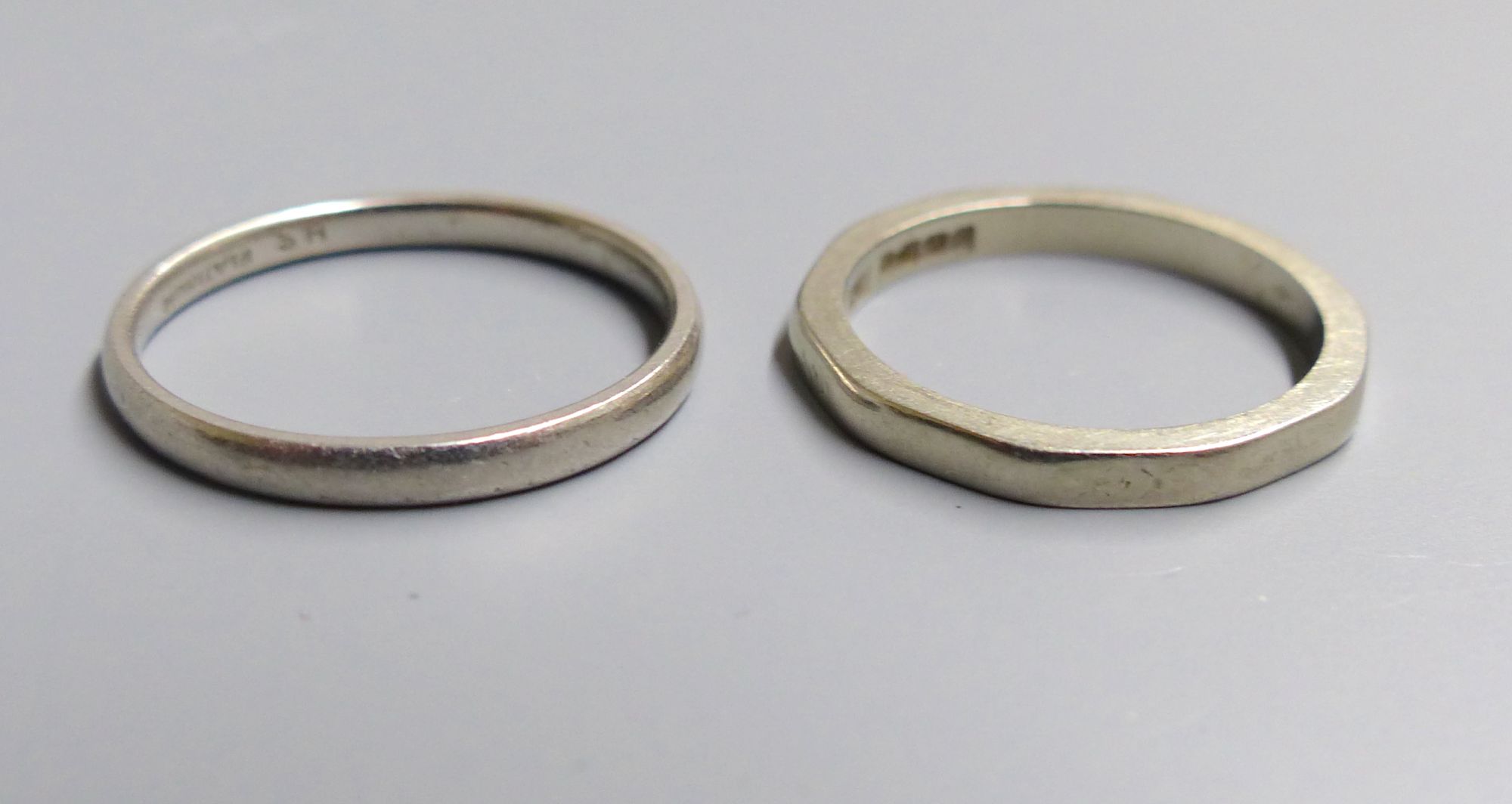 An 18ct gold decagonal wedding band (worn), size K, 2.9 grams and a white metal wedding band stamped Platinum, size M, 2.7 grams.